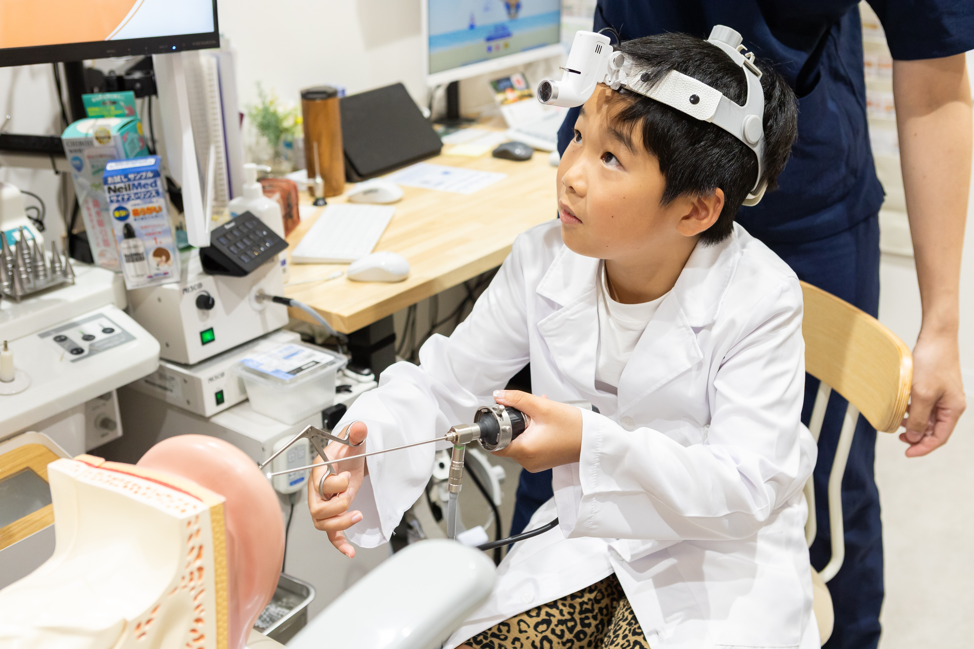 内視鏡を手に耳の模型を観察する子ども