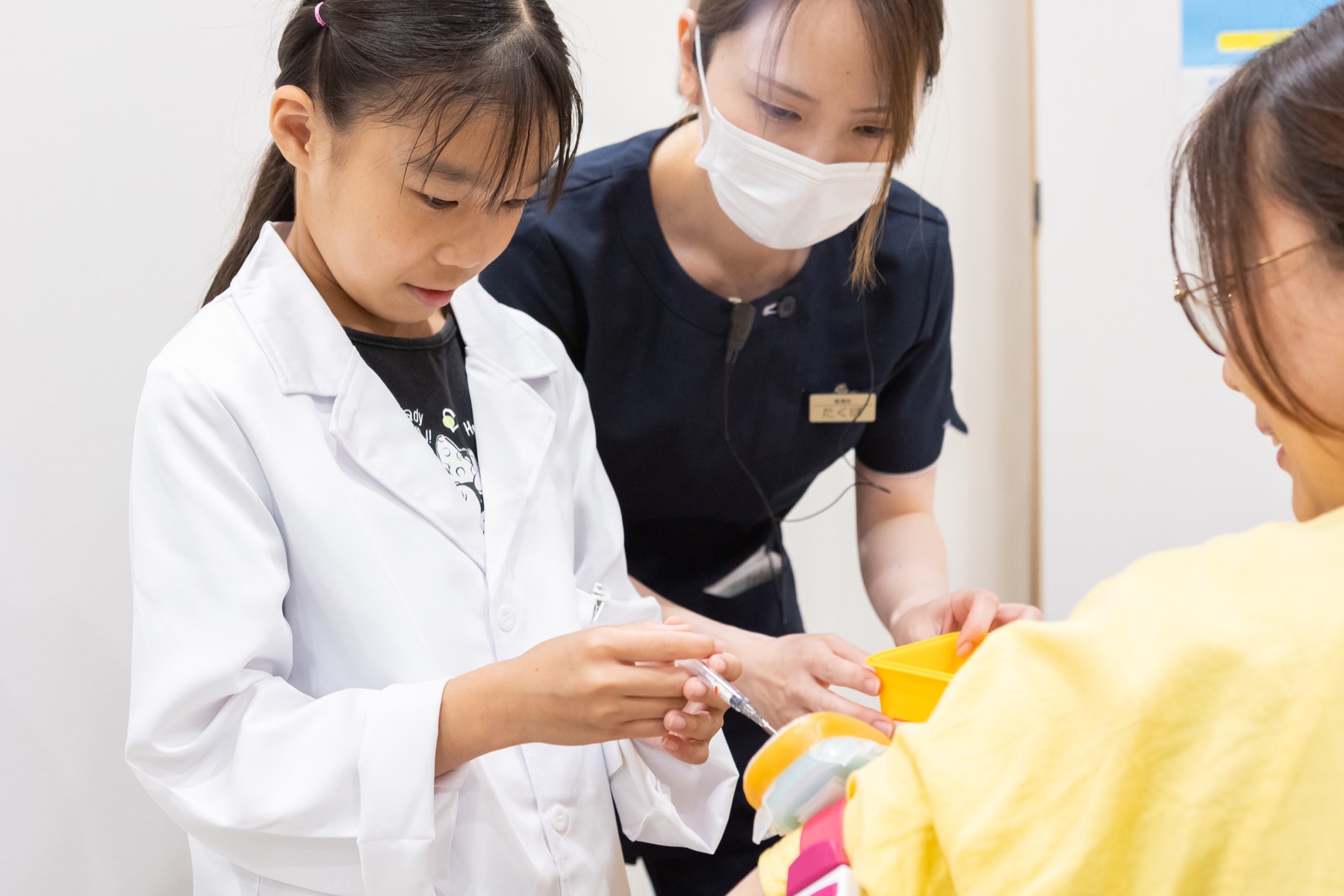 スタッフに教わりながら接種の手順を体験する子ども