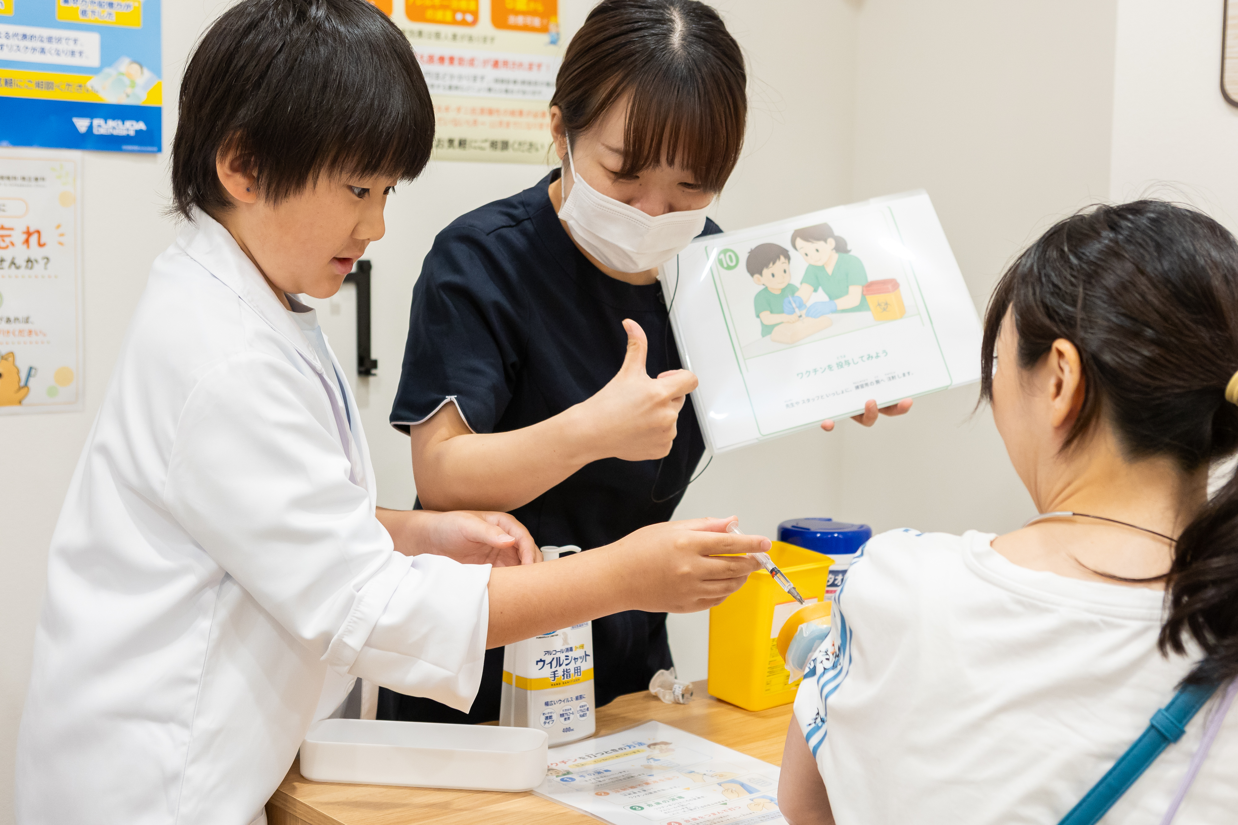 模型を使ってワクチン接種を体験する子ども